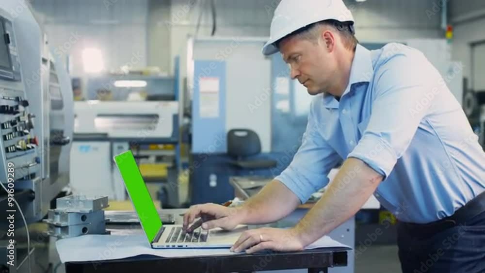 Engineer is Working on Notebook with Green Screen in Industrial Environment Engineer is Working on Notebook with Green Screen in Industrial Environment