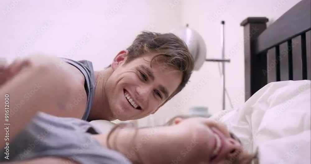 Attractive young couple making out in bed smiling engaged in foreplay