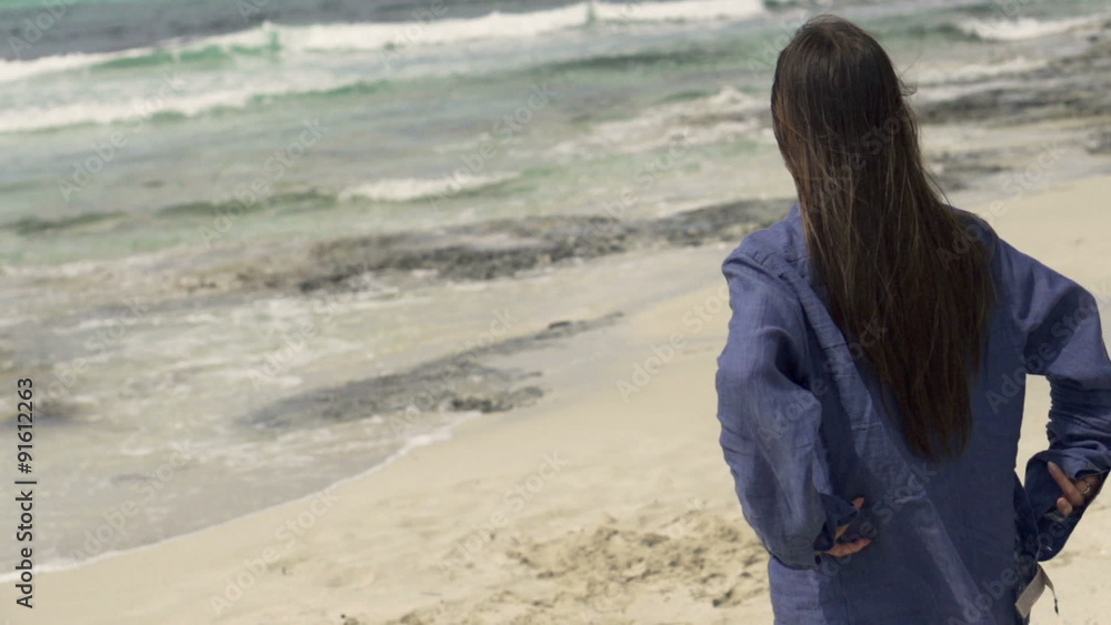 Young woman walking on beach and enjoying view Young woman walking on beach and enjoying view