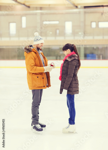 happy couple with engagement ring on skating rink