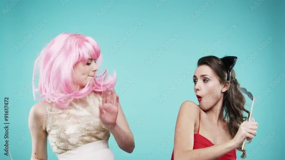 Girlfriends dancing wearing red dress and pink hair in slow motion party photo booth Girlfriends dancing wearing red dress and pink hair in slow motion party photo booth
