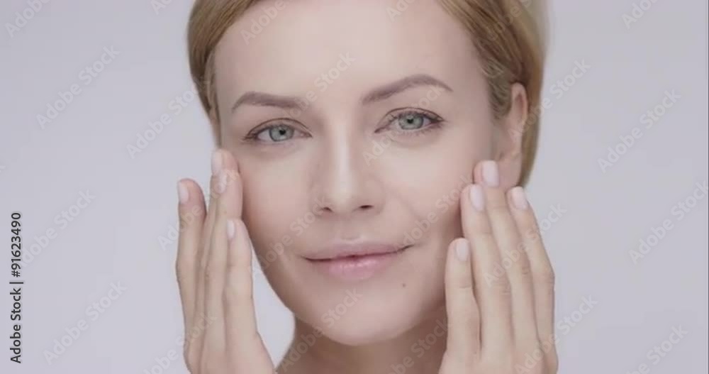 Beautiful healthy woman touching smooth skin on face in slow motion for beauty skincare concept on a grey background Red Epic Dragon Beautiful healthy woman touching smooth skin on face in slow motion for beauty skincare concept on a grey background Red Epic Dragon