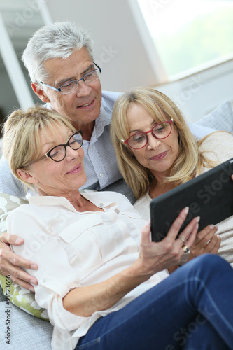 Group of senior friends with eyeglasses using digital tablet
