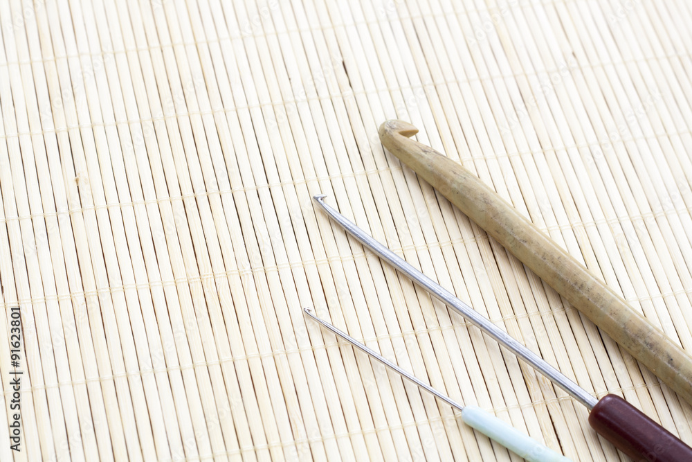 Crochet hooks on light makisu close-up, selective focus Crochet hooks on light makisu close-up, selective focus