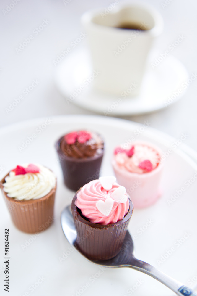 Small cup with heart shape chocolate on white plates