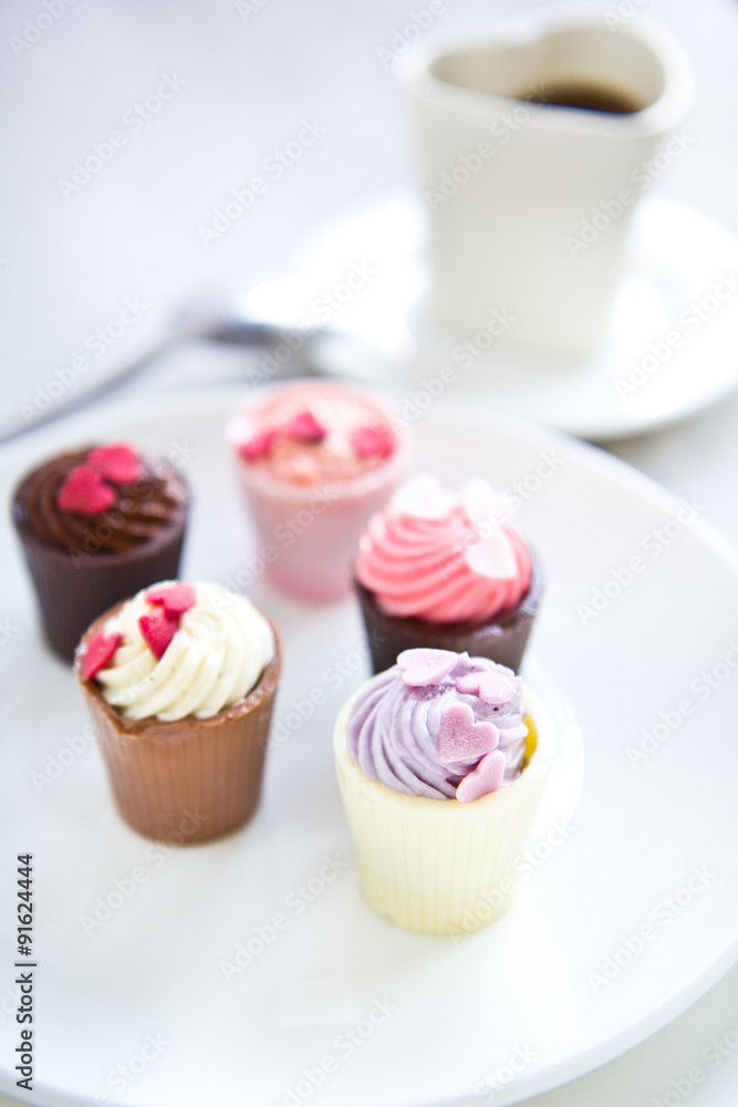 Small cup with heart shape chocolate on white plates Small cup with heart shape chocolate on white plates