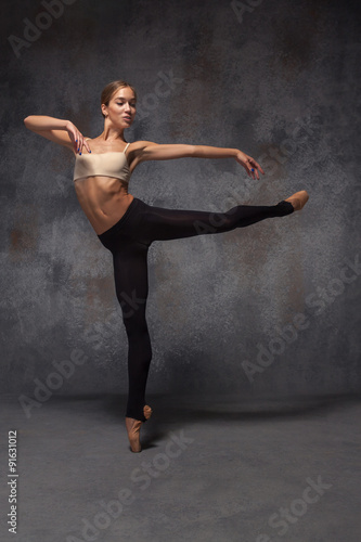 Young beautiful modern style dancer posing on a studio