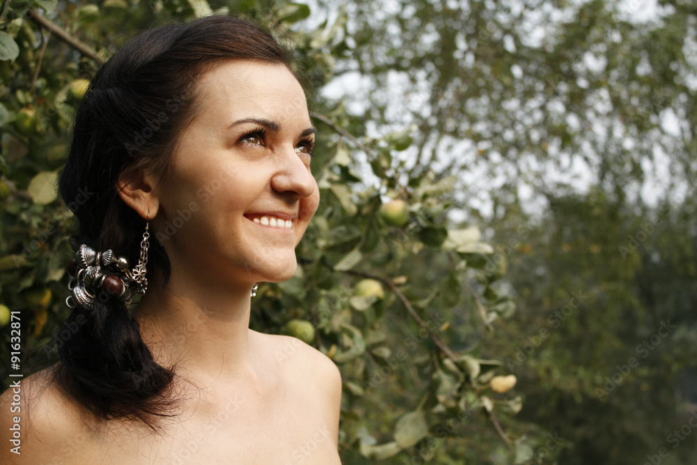 young beautiful European brunette woman smiling on the background of apple orchard young beautiful European brunette woman smiling on the background of apple orchard