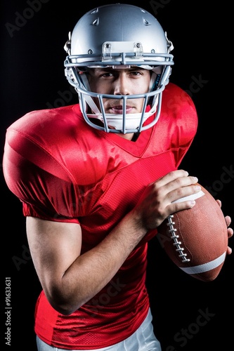 Portrait of determined sportsman holding American football
