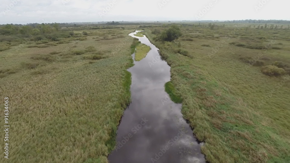 Low altitude aerial video of the slow moving Pine River in central Wisconsin, surrounded by sedge meadow wetland, marsh. The water is calm and reflects the sun and clouds. Low altitude aerial video of the slow moving Pine River in central Wisconsin, surrounded by sedge meadow wetland, marsh. The water is calm and reflects the sun and clouds.