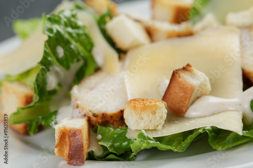 Caesar salad with chicken on wooden table