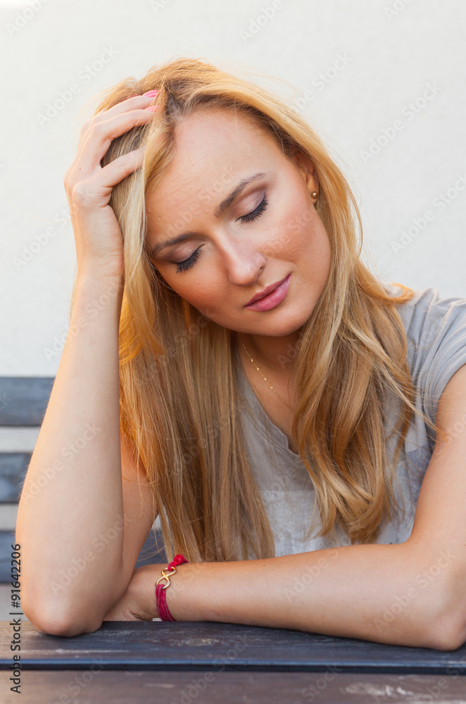 Blnd hair girl sitting behind the table and supporting head-hand Blnd hair girl sitting behind the table and supporting head-hand