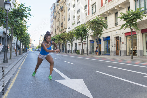 Beautiful sporty african woman running on road in the street.