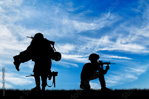  Silhouette of a soldier carries a wounded soldier