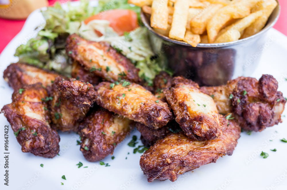 Chicken wings with sauce and golden French fries potatoes