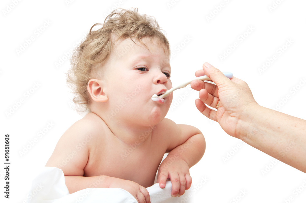 small child with curly hair, the mother feeds with spoon small child with curly hair, the mother feeds with spoon