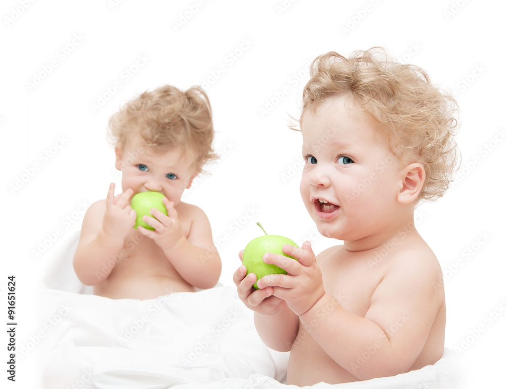children twins eating a green apple on white background children twins eating a green apple on white background