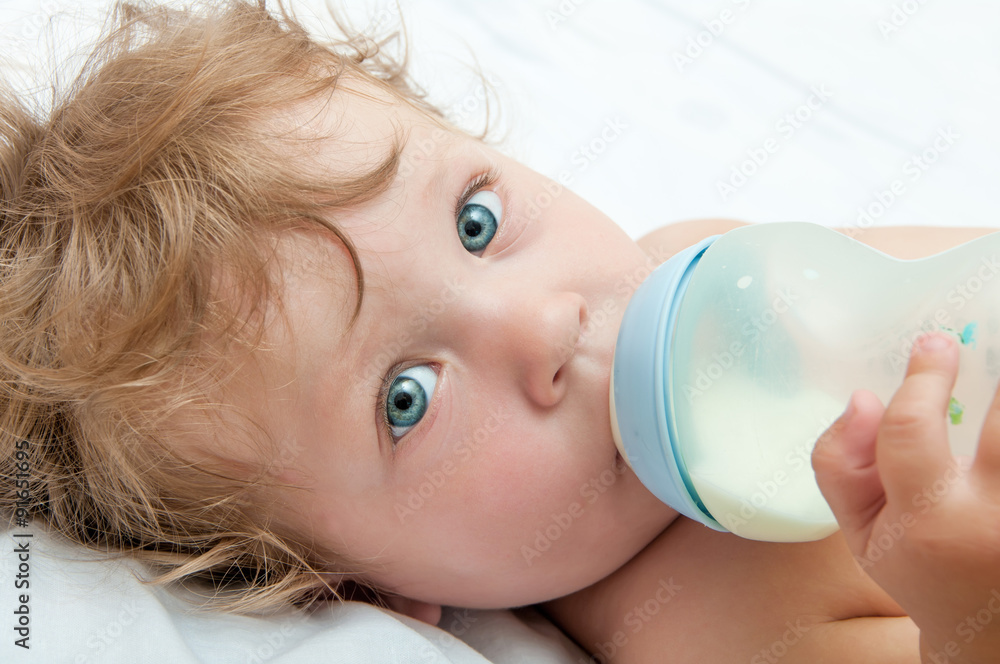 little curly-headed baby sucks a bottle of milk little curly-headed baby sucks a bottle of milk