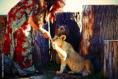 woman in ornamental dress and gold jewel with lion cub  © jozefklopacka
