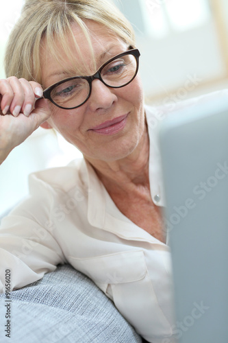Senior woman with eyeglasses connected on digital tablet