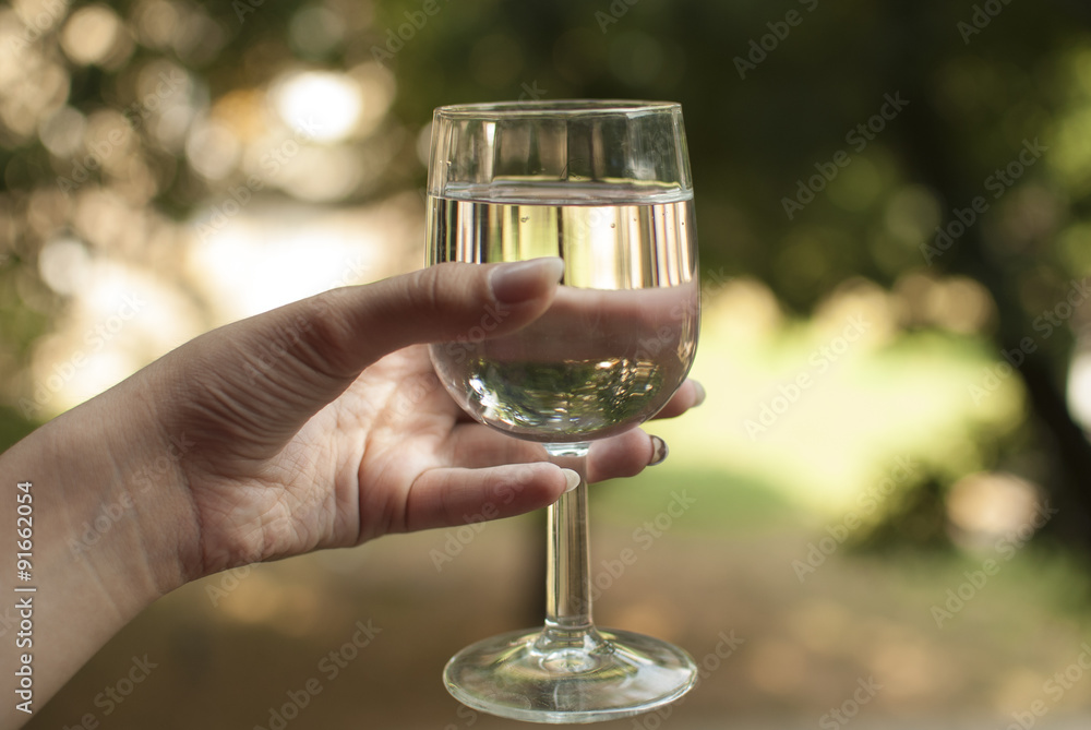 Hand of women holding glass with fresh water. 