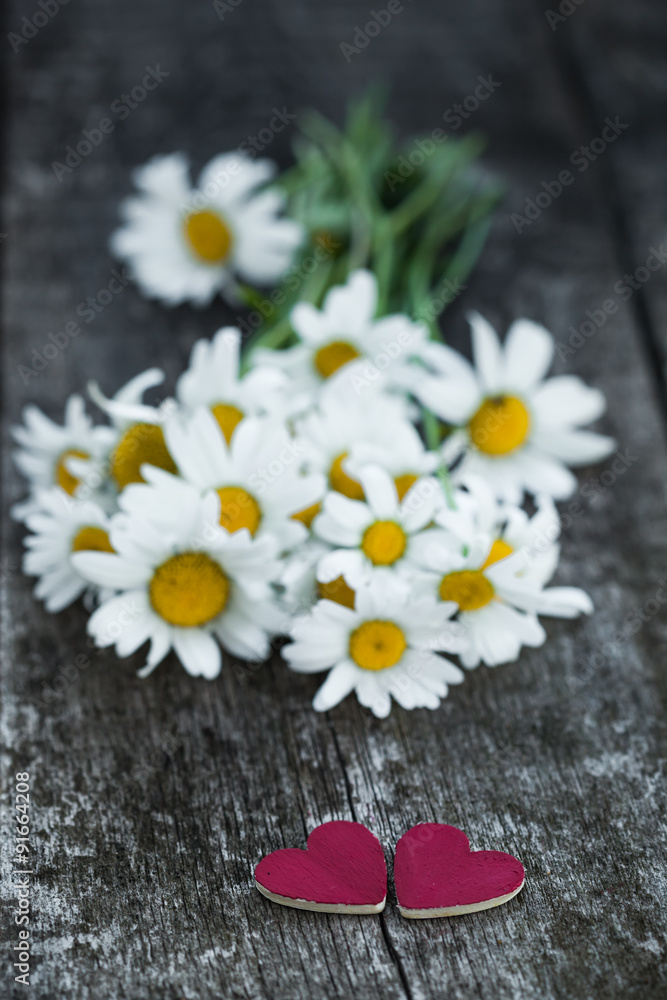 Obraz premium Beautiful fresh daisies decorated with hearts on wooden texture