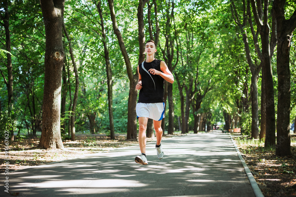 young caucasian male running in park. Teenager jogging in park