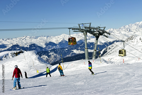 Skiing and snowboarding in high mountains, with ski lift in the background