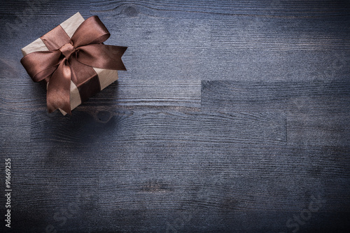 Boxed present with brown bow on vintage wooden board copyspace