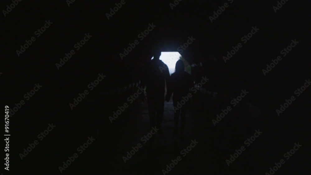A couple walks through a covered path in the woods. A couple walks through a covered path in the woods.