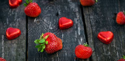 Strawberries and candy on wooden table