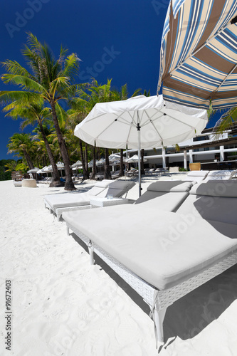 Sun umbrellas and beach beds on tropical coastline