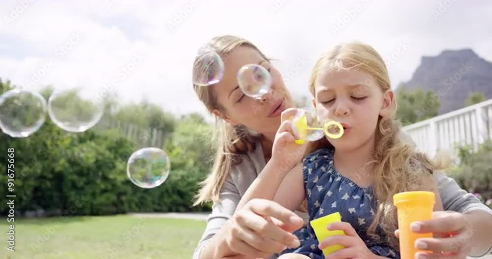 Mother and Daughter blowing bubbles in the yard happy family home Mother and Daughter blowing bubbles in the yard happy family home