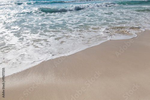 Sea waves with foam on white sandy beach