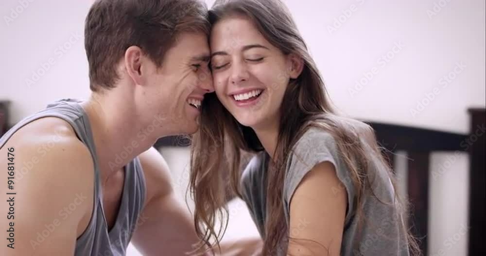 Attractive young couple making out in bed smiling engaged in foreplay
