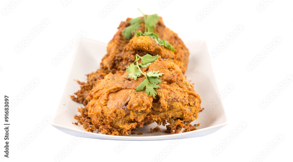 Popular Javanese dish Ayam Penyet or crispy fried chicken in a white plate over wooden background Popular Javanese dish Ayam Penyet or crispy fried chicken in a white plate over wooden background