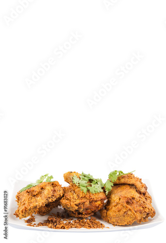 Popular Javanese dish Ayam Penyet or crispy fried chicken in a white plate over wooden background