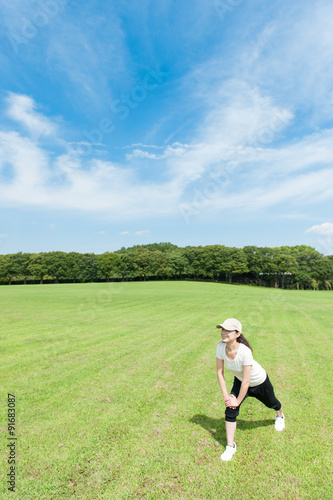 芝生の上でストレッチをする日本人女性 © beeboys
