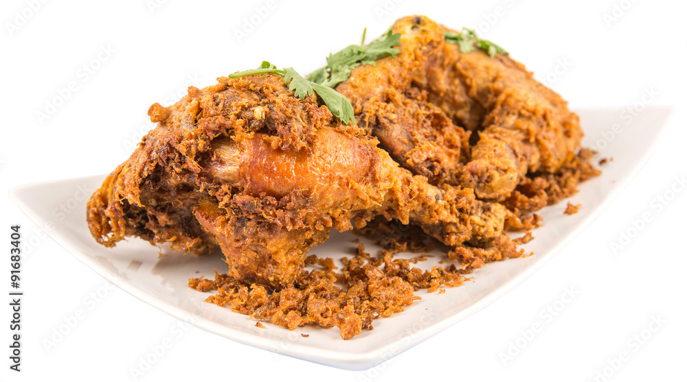 Popular Javanese dish Ayam Penyet or crispy fried chicken in a white plate over wooden background Popular Javanese dish Ayam Penyet or crispy fried chicken in a white plate over wooden background