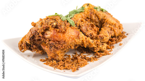 Popular Javanese dish Ayam Penyet or crispy fried chicken in a white plate over wooden background photo