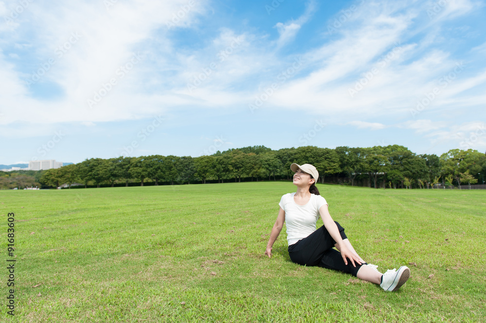 芝生の上でストレッチをする日本人女性