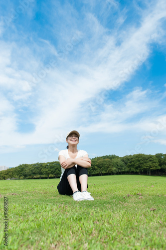 芝生で三角座りをしている女性