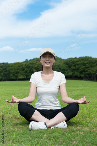 芝生の上に座って瞑想している女性