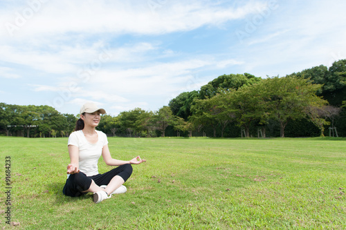 芝生の上に座って瞑想している女性