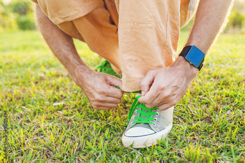 Detail of a man tying his shoe strings with a smart watch on a man's wrist. Template for sport smartwatch app design