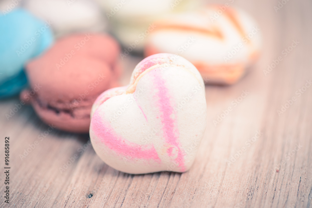 A lot of french colorful macarons in .heart shape on a woody flo A lot of french colorful macarons in .heart shape on a woody flo