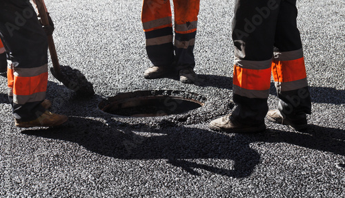 Quadro em tela Asphalting in progress, workers near sewer manhole