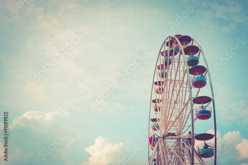 Ferris wheel on cloudy sky background vintage color