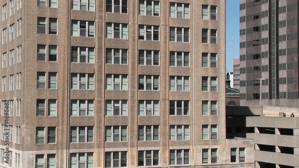 Zoom in to the windows of an older office building to show the blinds askew. Zoom in to the windows of an older office building to show the blinds askew.