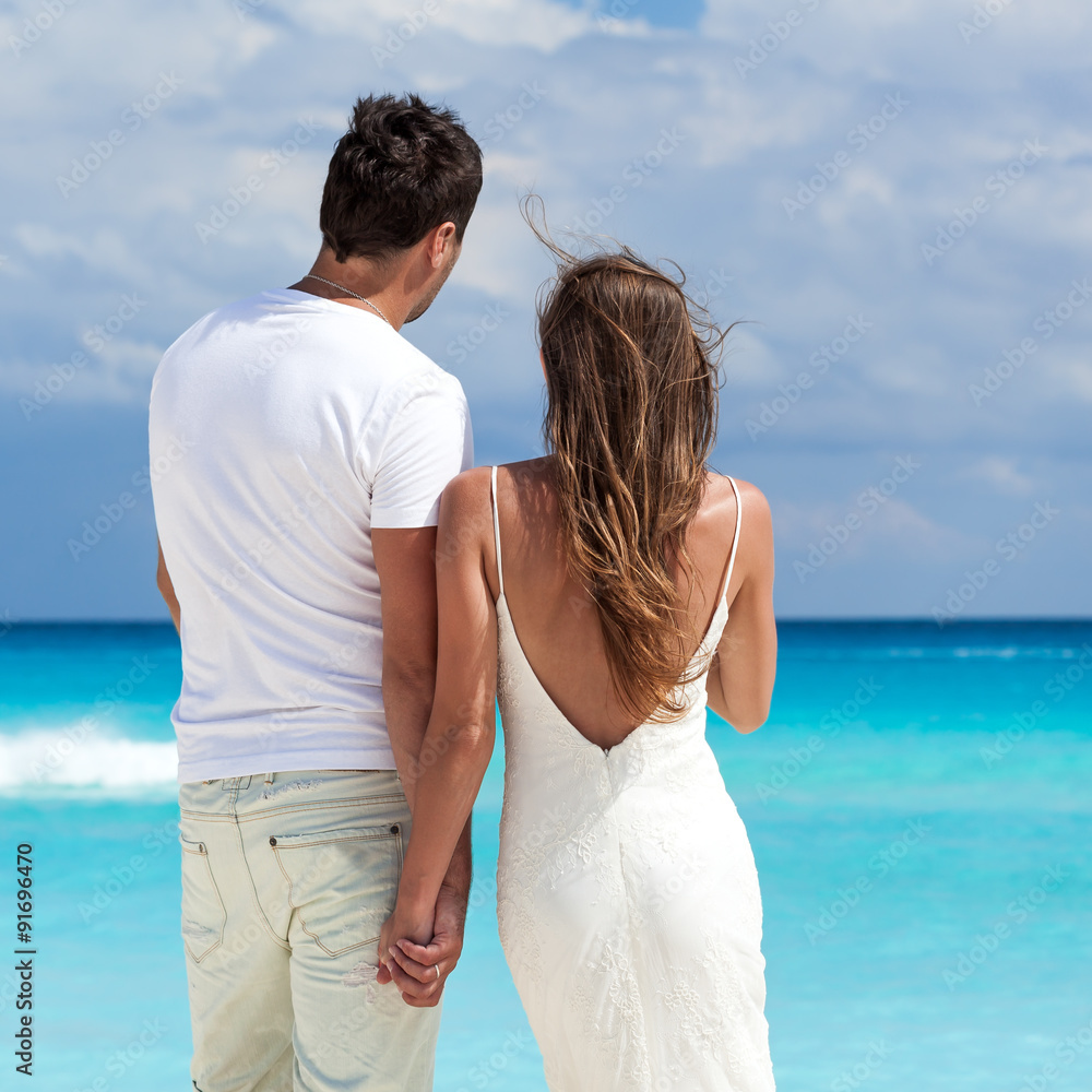 Newlyweds in love on beach looking to the sea Newlyweds in love on beach looking to the sea